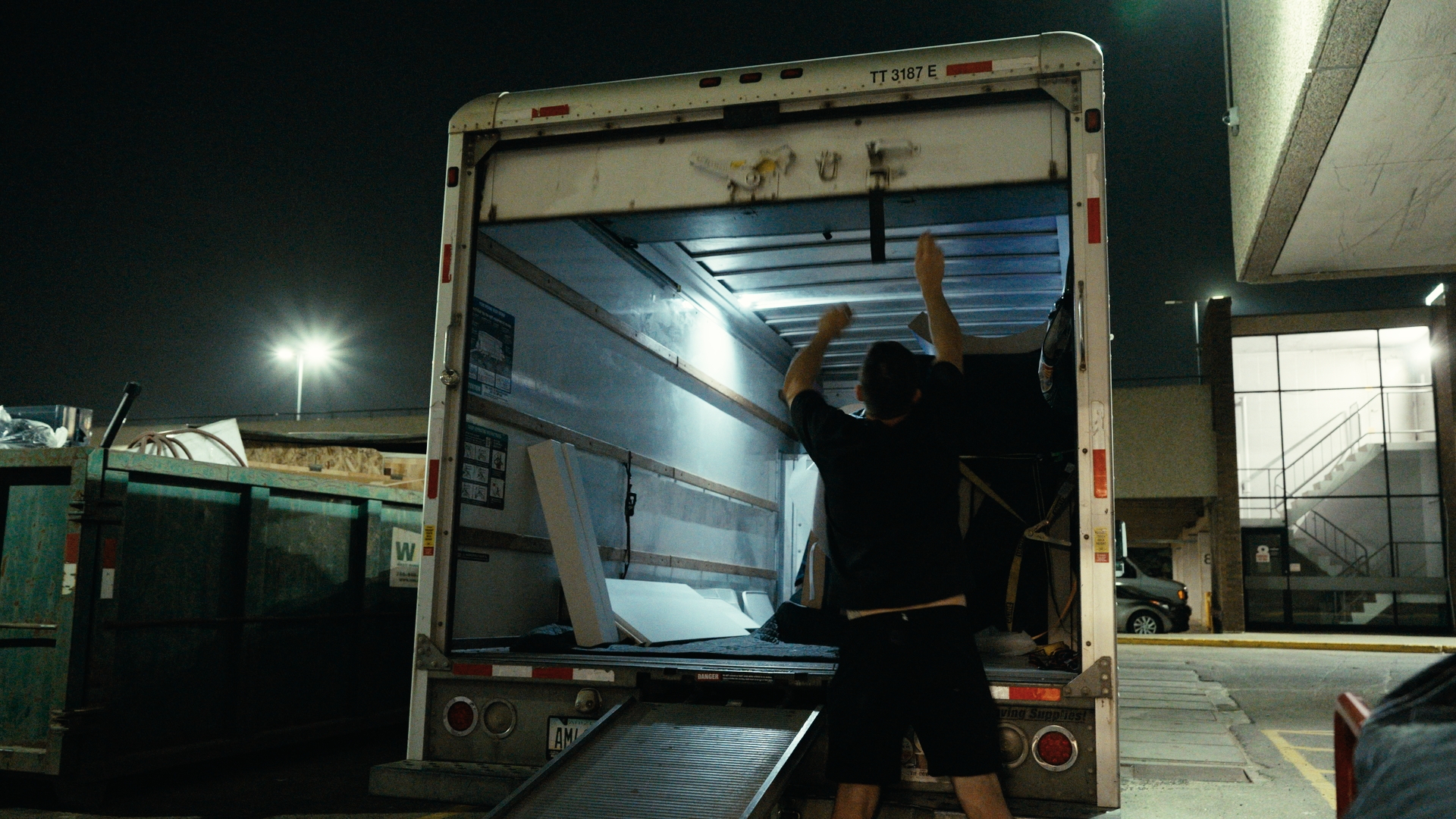 Workers unload a truck beside a building at night — Time Store