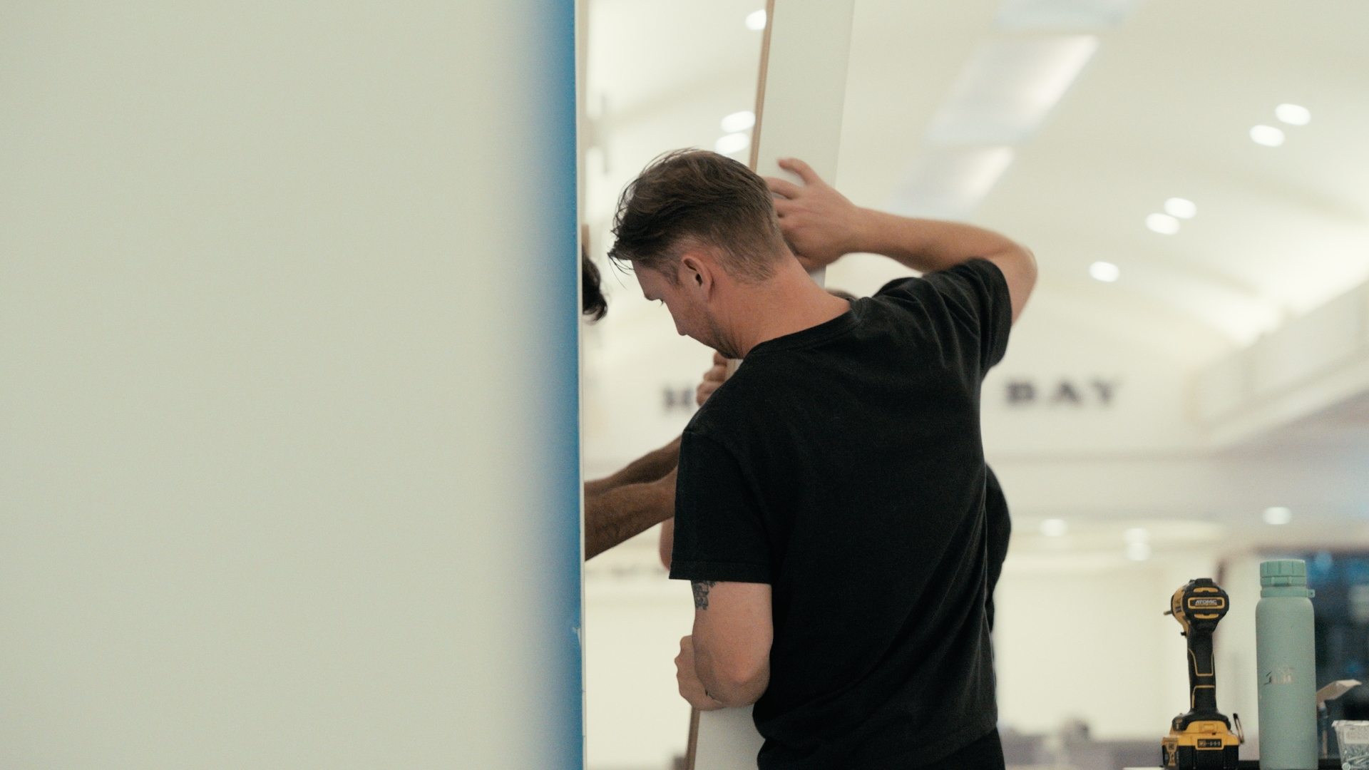A man assembles a display wall inside a shopping centre — Time Store