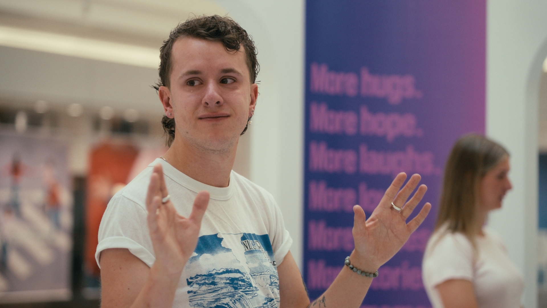 A man gestures beside a purple display panel — Time Store