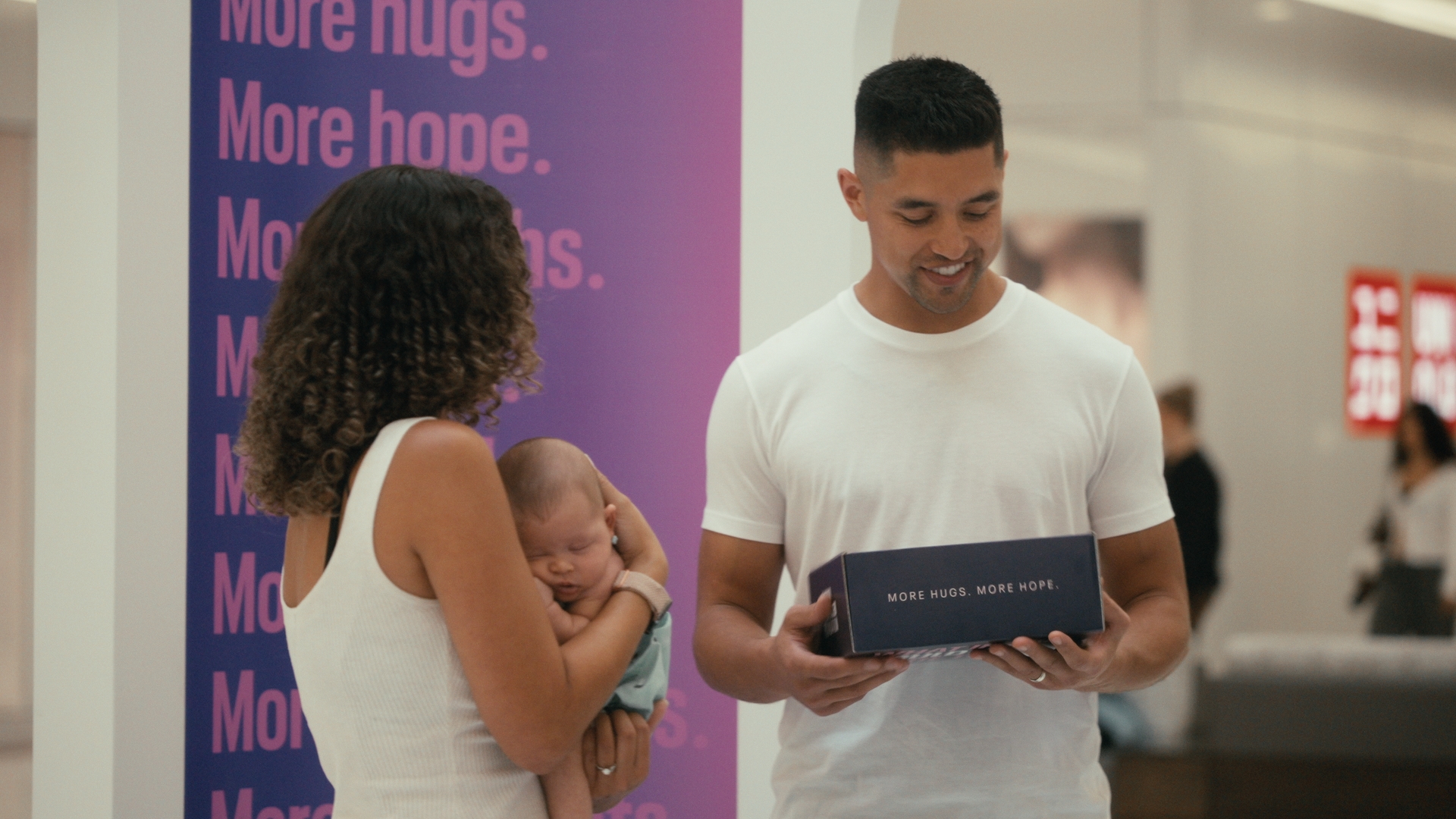 A man holds a box beside a woman carrying a baby — Time Store