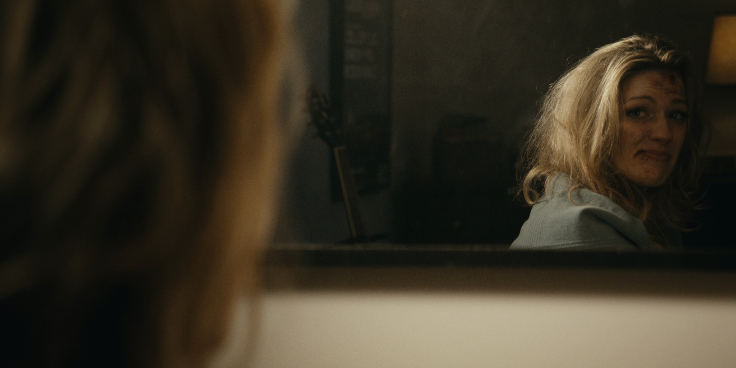 A woman looks over her shoulder in a wall mirror — Trinkets
