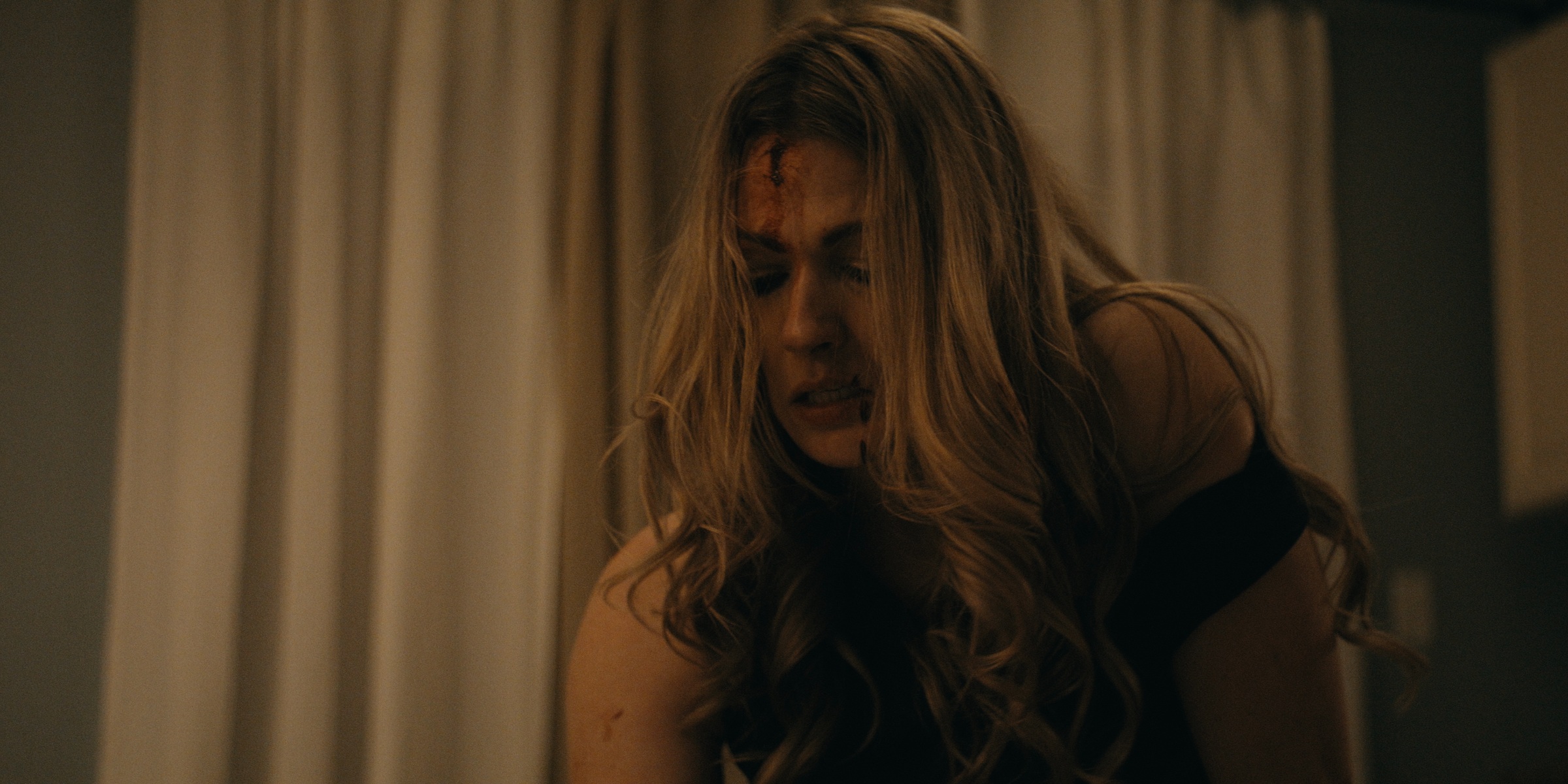 A woman with tousled hair stands in front of pale curtains — Trinkets